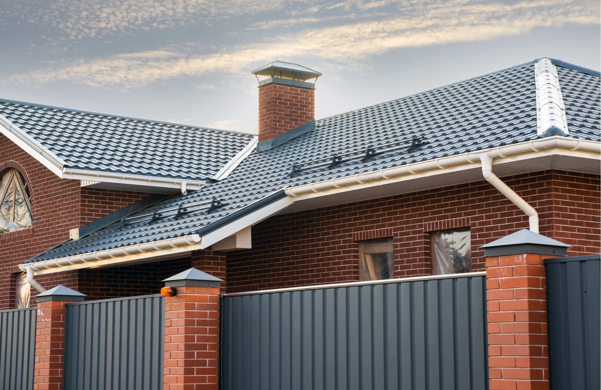 A brick home with gutters and downspouts along the roofline