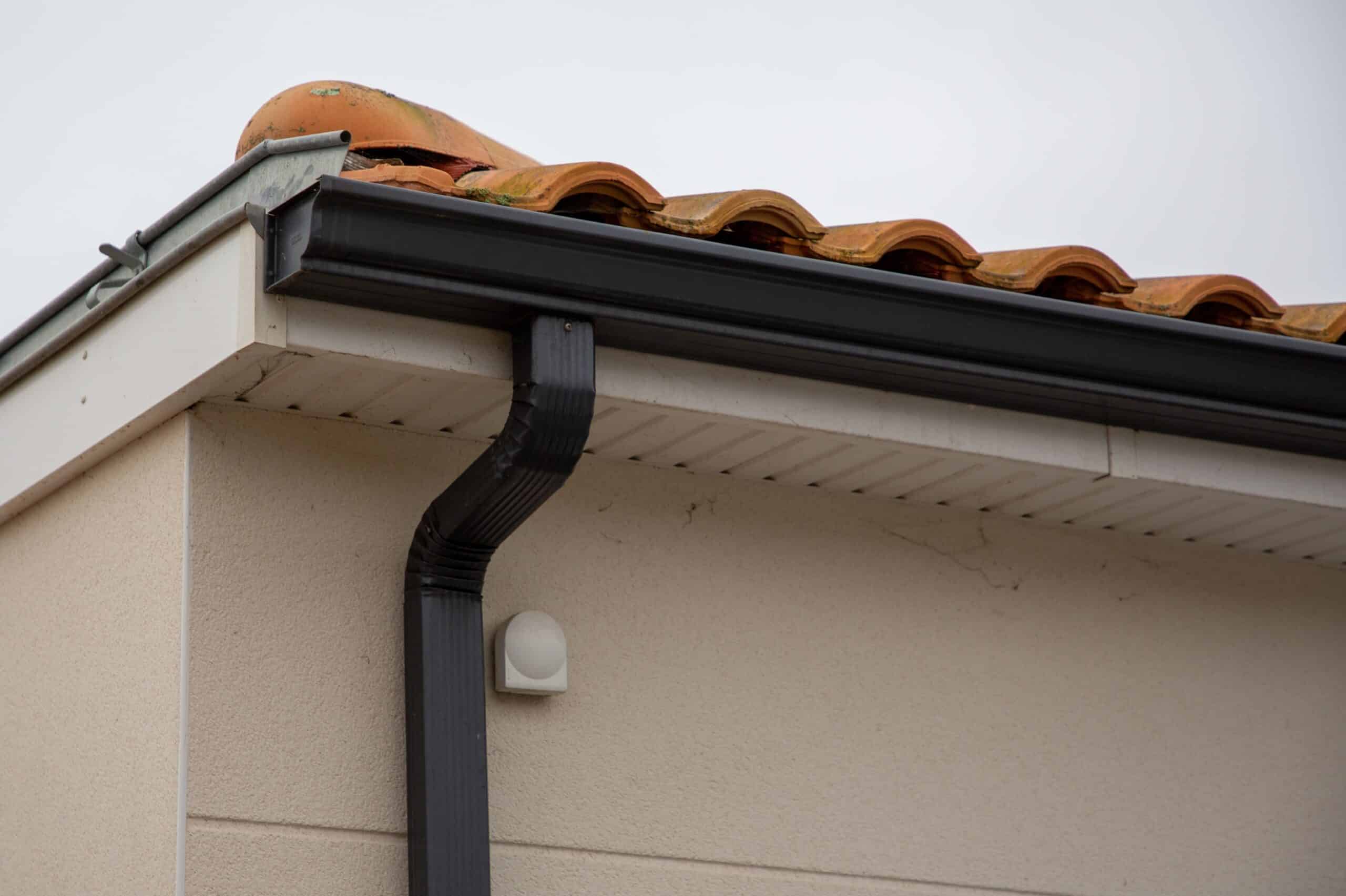 Seamless gutter and downspout installed on a stucco home